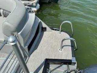 Slide: The Image of 2022 Bennington QX 23 Quad Bench boat with swim ladder and seating, docked on a lake. - 7