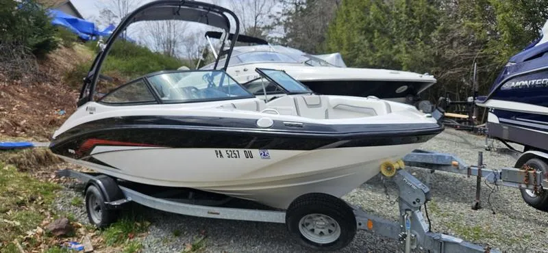 Slide: The Image of 2018 Yamaha AR190 boat on trailer, parked outdoors, surrounded by trees and other boats. - 1