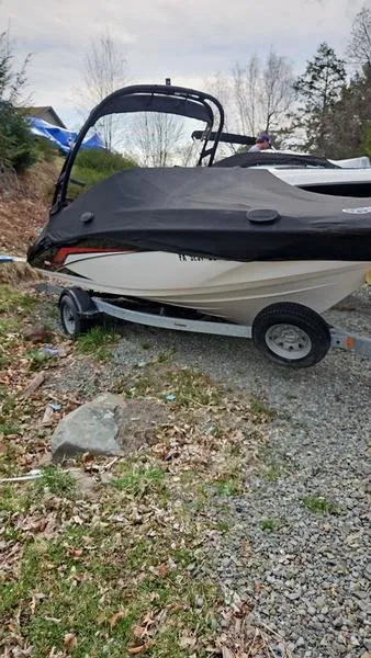 Slide: The Image of 2018 Yamaha AR190 boat on trailer, covered, parked on gravel path. - 2