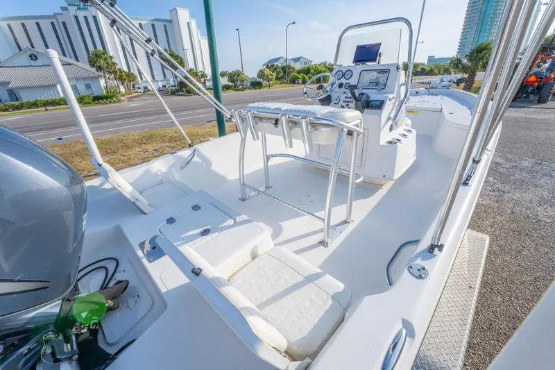 Slide: The Image of 2011 NauticStar 2110 Nautic Bay boat interior with console and seating, parked near buildings. - 10