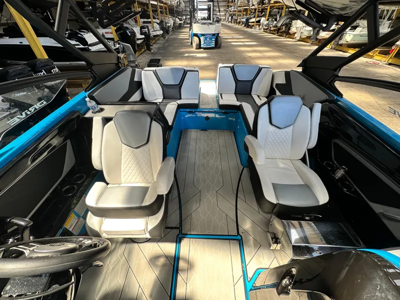 Slide: The Image of 2023 Yamaha Boats 255XD interior with modern seating and sleek design in a showroom. - 12