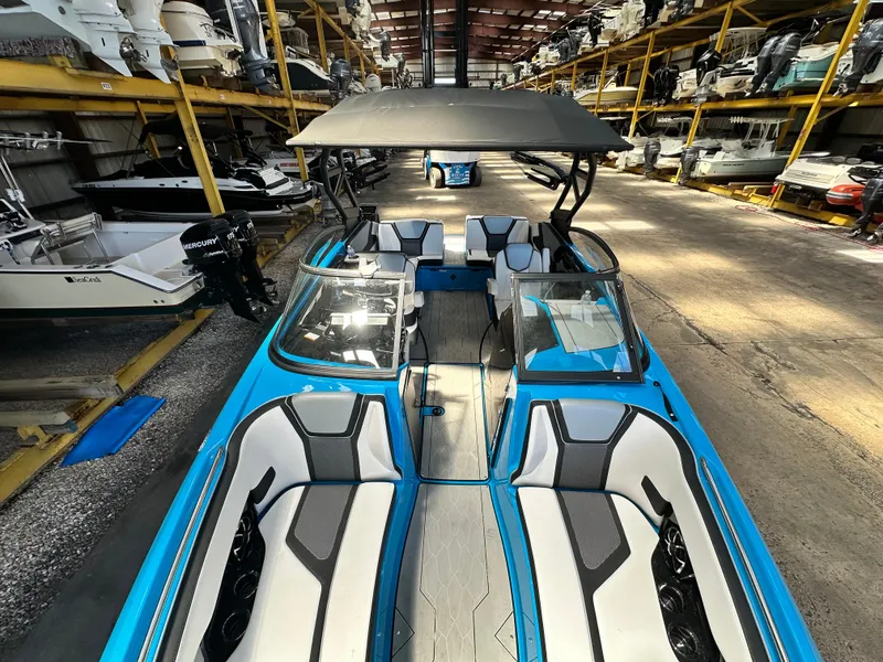 Slide: The Image of 2023 Yamaha Boats 255XD in storage, featuring sleek blue and white design with spacious seating. - 15