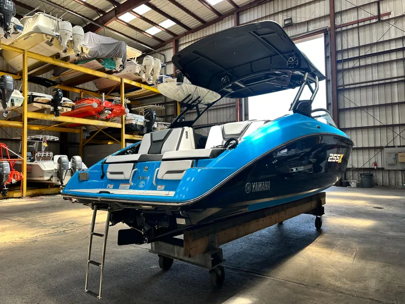 Slide: The Image of 2023 Yamaha Boats 255XD in warehouse, blue and black design, rear view. - 4
