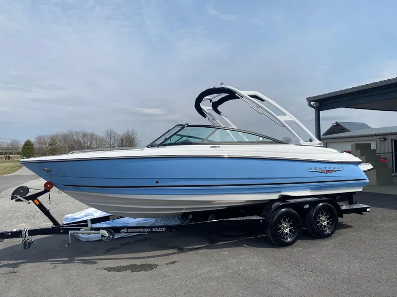Slide: The Image of 2025 Monterey 224FS boat on trailer, blue and white design, parked outdoors. - 1