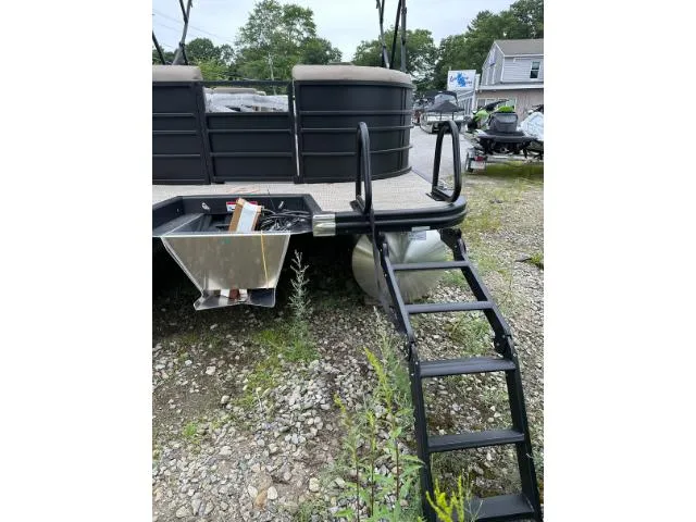 Slide: The Image of 2024 Bennington 23 LSRC pontoon boat with ladder on gravel surface. - 8