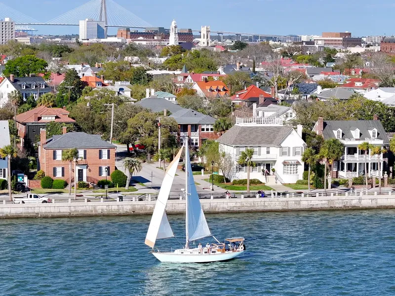 Slide: The Image of Sailboat cruising near a scenic waterfront cityscape with historic architecture and a distant bridge. - 16