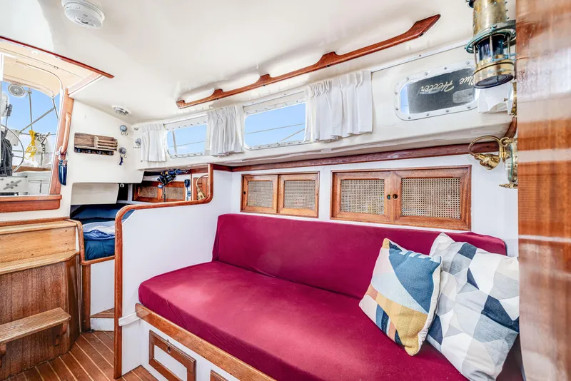 Slide: The Image of Interior of a 1981 Bristol 40 sailboat with red seating and decorative pillows. - 22