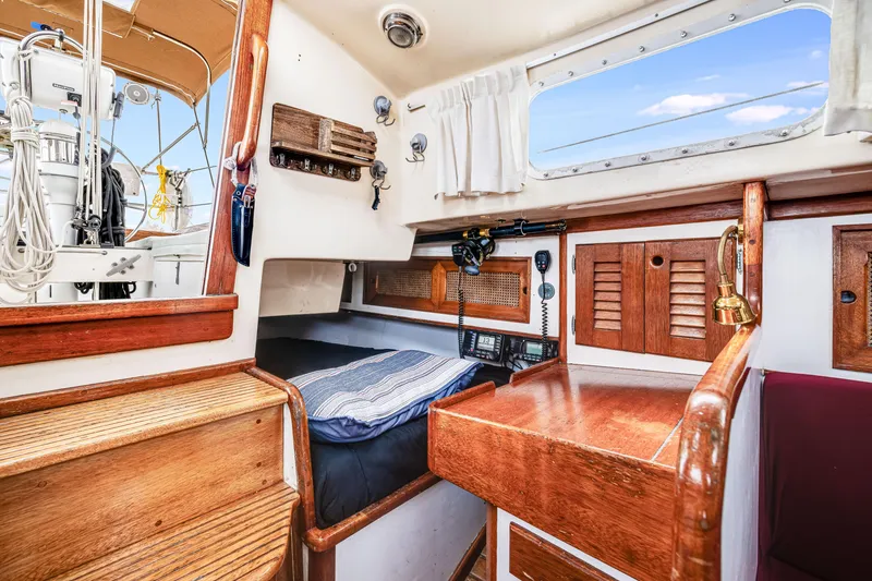 Slide: The Image of Interior of a 1981 Bristol 40 sailboat, featuring wooden cabinetry and a cozy sleeping area. - 25