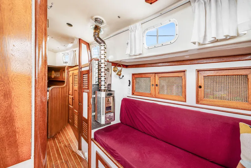 Slide: The Image of 1981 Bristol 40 yacht interior with wood paneling, red seating, and a compact stove. - 27