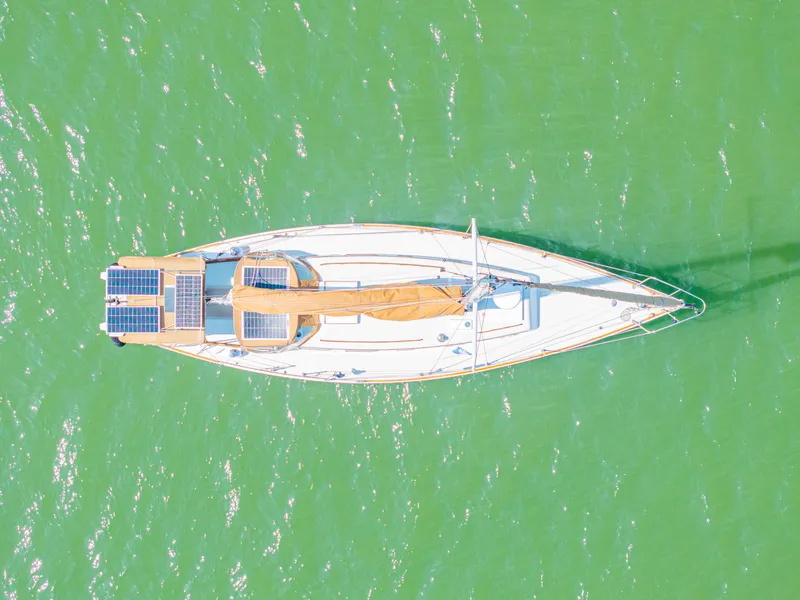 Slide: The Image of Aerial view of 1981 Bristol 40 sailboat with solar panels on green water. - 3
