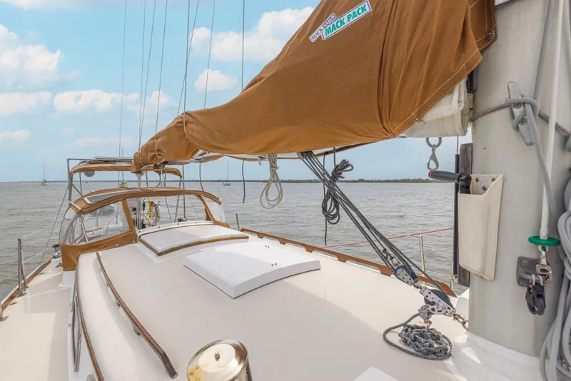 Slide: The Image of 1981 Bristol 40 sailboat deck with brown sail cover, sailing on calm waters. - 38