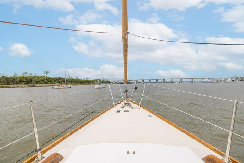 Slide: The Image of Bow view of 1981 Bristol 40 sailboat on a calm river with bridge in background. - 39