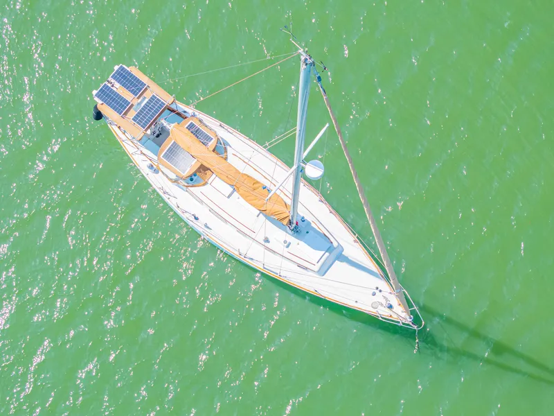 Slide: The Image of Aerial view of 1981 Bristol 40 sailboat with solar panels on green water. - 4