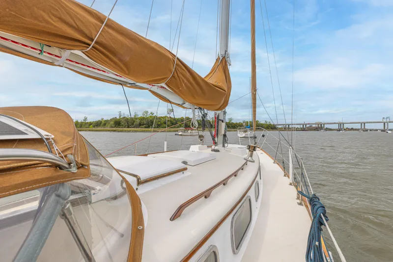 Slide: The Image of 1981 Bristol 40 sailboat on calm water, featuring tan sails and clear sky. - 47