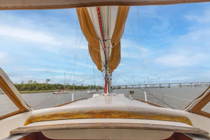 Slide: The Image of 1981 Bristol 40 sailboat deck view with mast, sails, and scenic waterway. - 48
