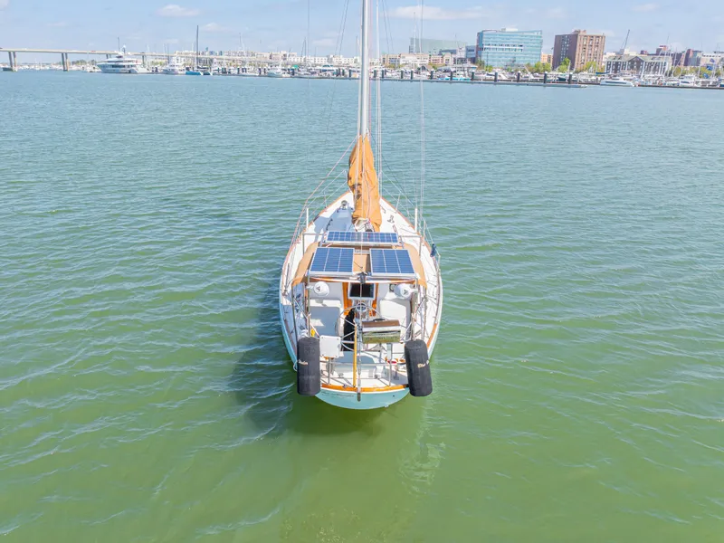 Slide: The Image of 1981 Bristol 40 sailboat with solar panels on calm water, cityscape in background. - 9
