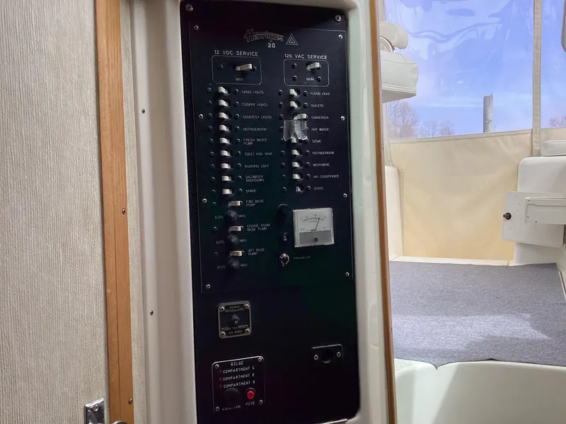 Slide: The Image of Electrical panel inside a 2001 Henriques 28 Express boat, featuring various switches and controls. - 23