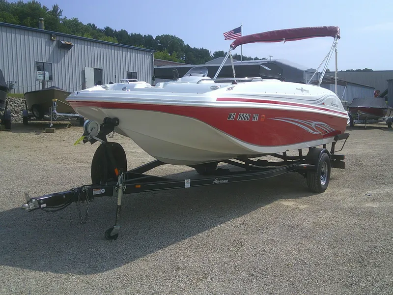 Slide: The Image of 2011 Hurricane SunDeck Sport 188 IO boat on trailer, red and white design, parked outdoors. - 16