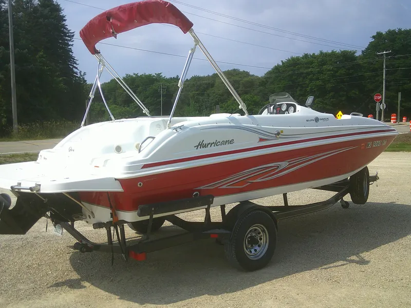 Slide: The Image of 2011 Hurricane SunDeck Sport 188 IO boat on trailer, red and white design, parked outdoors. - 17