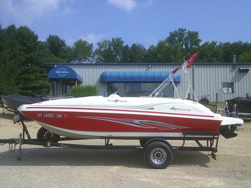 Slide: The Image of 2011 Hurricane SunDeck Sport 188 IO boat on trailer, red and white design, parked outdoors. - 20