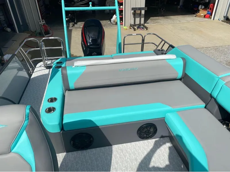 Slide: The Image of 2025 Berkshire 25 SB2 STS boat interior with teal and gray seating, cup holders, and speakers. - 18