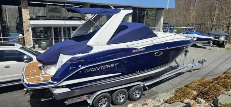 Slide: The Image of 2015 Monterey 295 Sport Yacht on trailer, blue cover, parked outside dealership. - 25