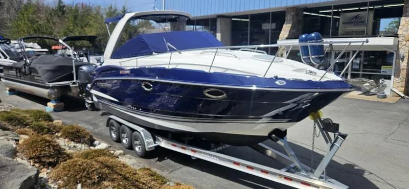 Slide: The Image of 2015 Monterey 295 Sport Yacht on trailer, blue and white exterior, parked outdoors. - 26