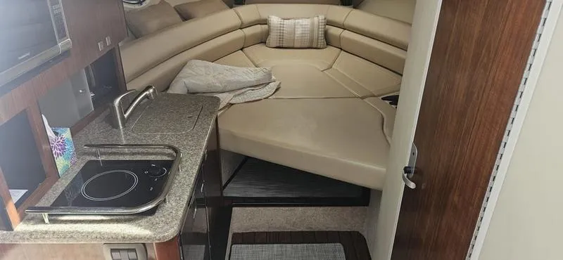 Slide: The Image of 2015 Monterey 295 Sport Yacht interior with kitchenette and cozy sleeping area. - 6