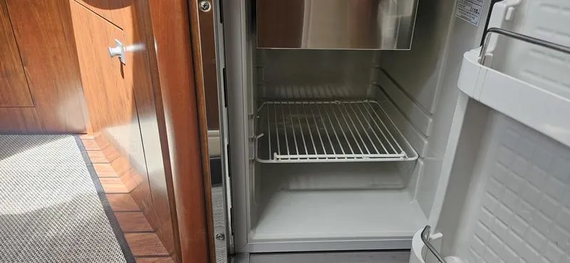 Slide: The Image of Open refrigerator inside 2015 Monterey 295 Sport Yacht, showcasing interior shelving. - 7