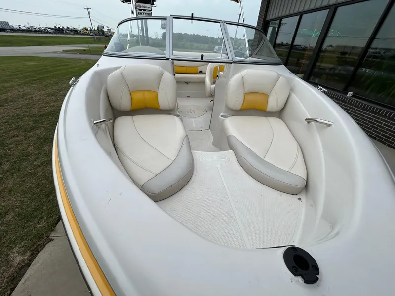 Slide: The Image of 2010 Tahoe Q5SI boat with white and yellow seating, docked near a building. - 10