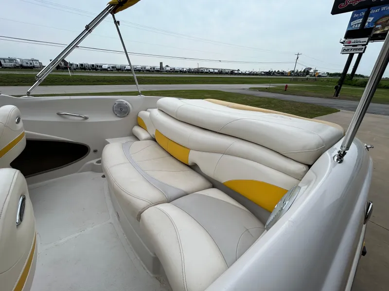 Slide: The Image of 2010 Tahoe Q5SI boat interior with white and yellow seating, parked outdoors. - 12