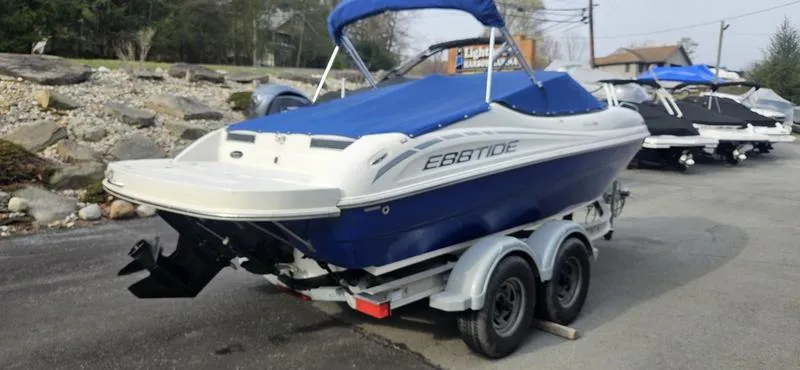 Slide: The Image of 2010 Ebbtide 202 SE Bow Rider boat on trailer, blue and white design, parked outdoors. - 1