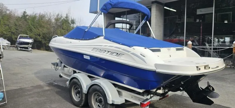 Slide: The Image of 2010 Ebbtide 202 SE Bow Rider boat on trailer, blue and white, parked outdoors. - 2