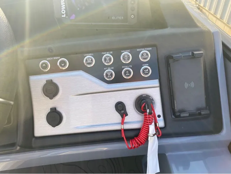 Slide: The Image of Control panel of 2025 Berkshire 25RFX STS boat with various switches and a phone holder. - 8