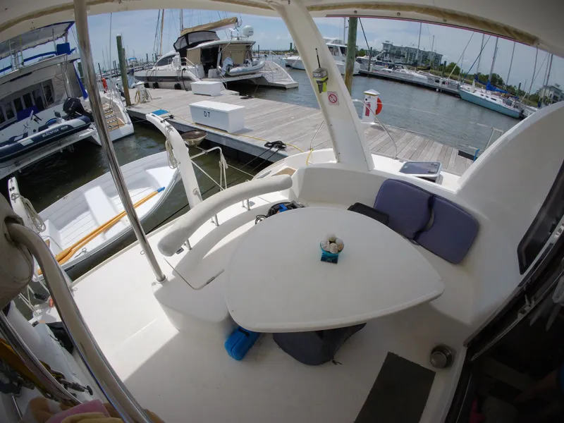 Slide: The Image of 2005 Leopard 40 catamaran cockpit with seating, table, and marina view. - 23