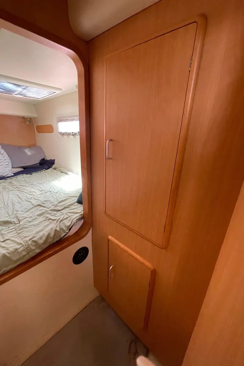Slide: The Image of Interior of a 2005 Leopard 40 catamaran showing a cozy bedroom and wooden cabinetry. - 43