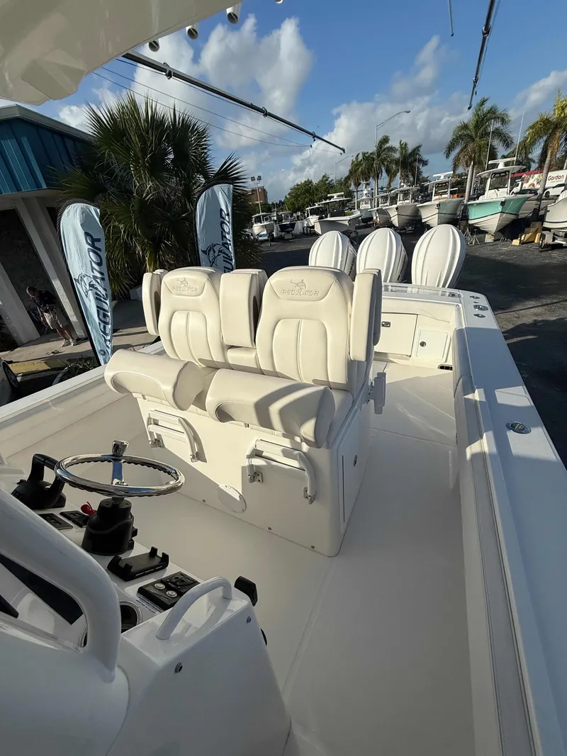Slide: The Image of 2023 Regulator 34 boat interior with plush seating and steering console, docked under a sunny sky. - 20