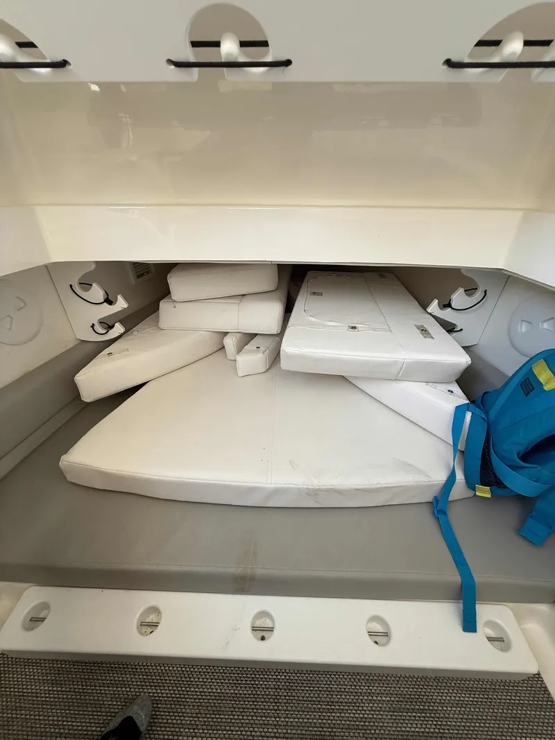 Slide: The Image of 2023 Regulator 34 boat storage compartment with white cushions and a blue bag. - 23