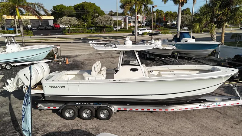 Slide: The Image of 2023 Regulator 34 boat on trailer, parked outdoors with palm trees in the background. - 3