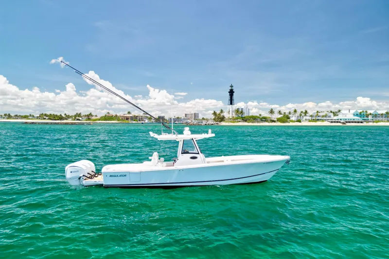 Slide: The Image of 2023 Regulator 34 boat on clear blue water near a coastal lighthouse. - 42