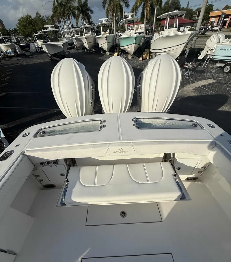 Slide: The Image of 2023 Regulator 34 boat with triple engines, docked in a marina with palm trees. - 8