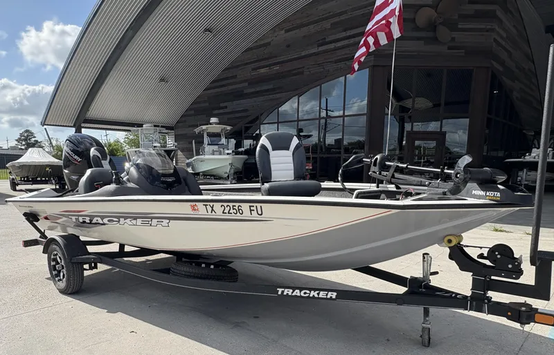 Slide: The Image of 2020 Tracker Pro Team 175 boat on trailer, parked outside a modern building with an American flag. - 4