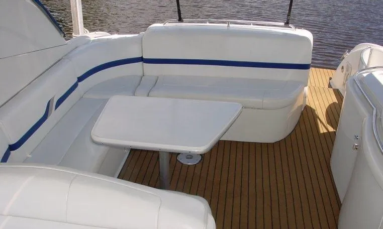 Slide: The Image of 2002 Formula 400 SS boat interior with white seating and table on wooden deck. - 6