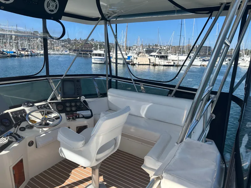 Slide: The Image of 1991 Symbol 39 Sedan Sportfisher interior with helm, seating, and marina view. - 14