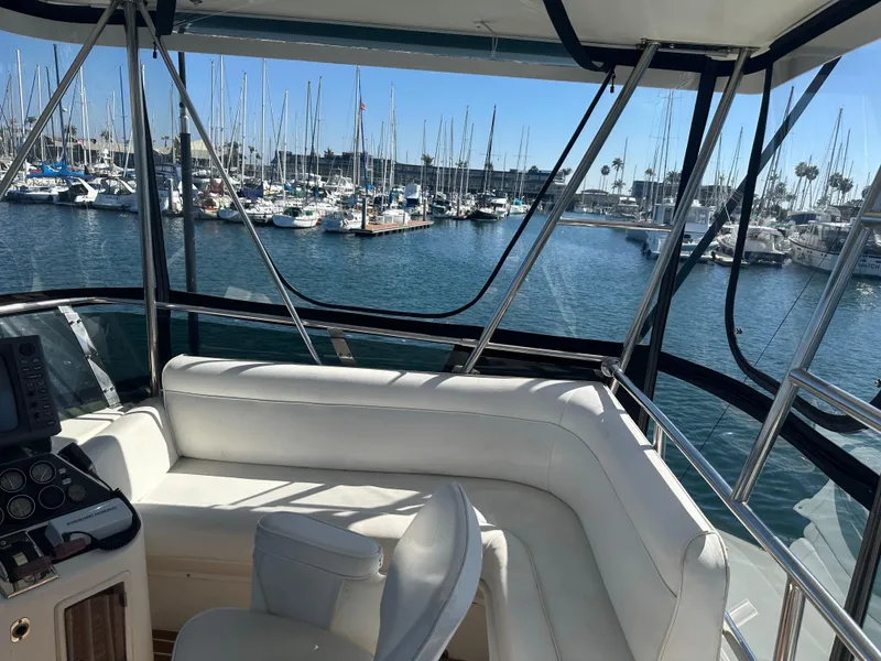 Slide: The Image of 1991 Symbol 39 Sedan Sportfisher interior with marina view, featuring white seating and control panel. - 15