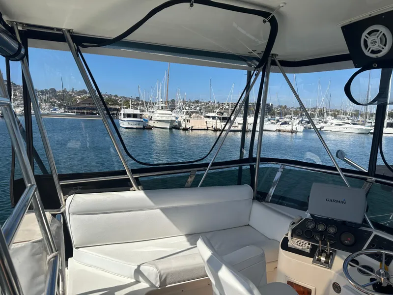 Slide: The Image of 1991 Symbol 39 Sedan Sportfisher interior with marina view, featuring white seating and navigation equipment. - 16