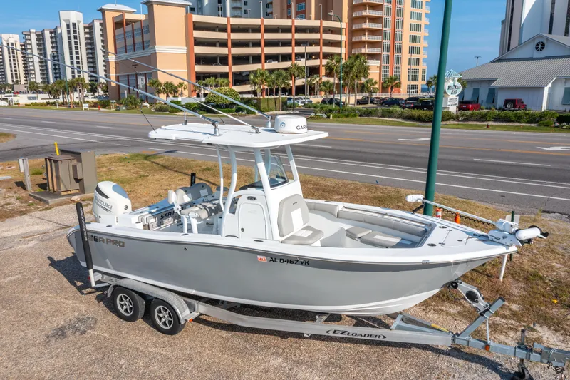 Slide: The Image of 2019 Sea Pro 239 DLX boat on trailer, parked near coastal buildings. - 0