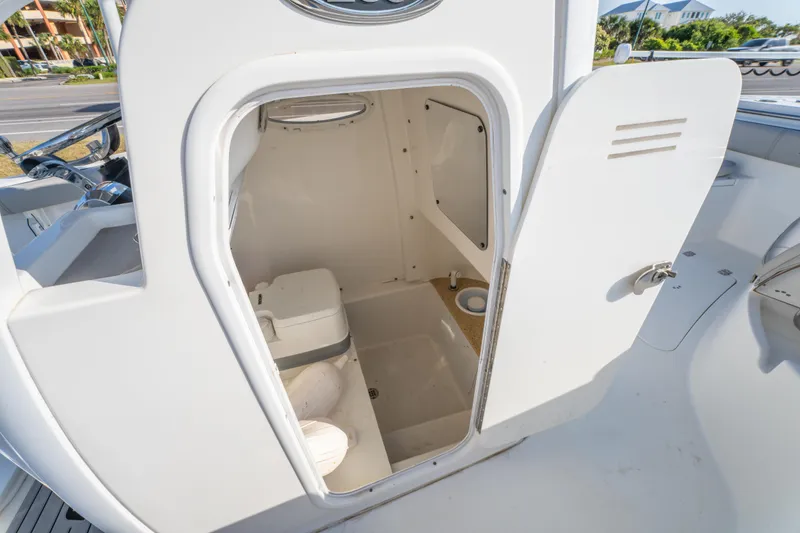 Slide: The Image of 2019 Sea Pro 239 DLX boat interior with open compartment showing a compact marine toilet. - 27