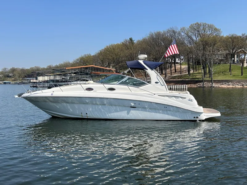 The Image of 2006 Sea Ray 320 Sundancer yacht on a calm lake with trees in the background. - 0