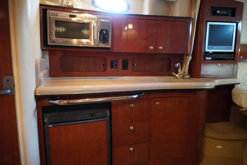Slide: The Image of 2006 Sea Ray 320 Sundancer interior kitchen with microwave, sink, and wooden cabinetry. - 23
